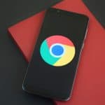 Android smartphone with Google Chrome logo on screen, on black surface.